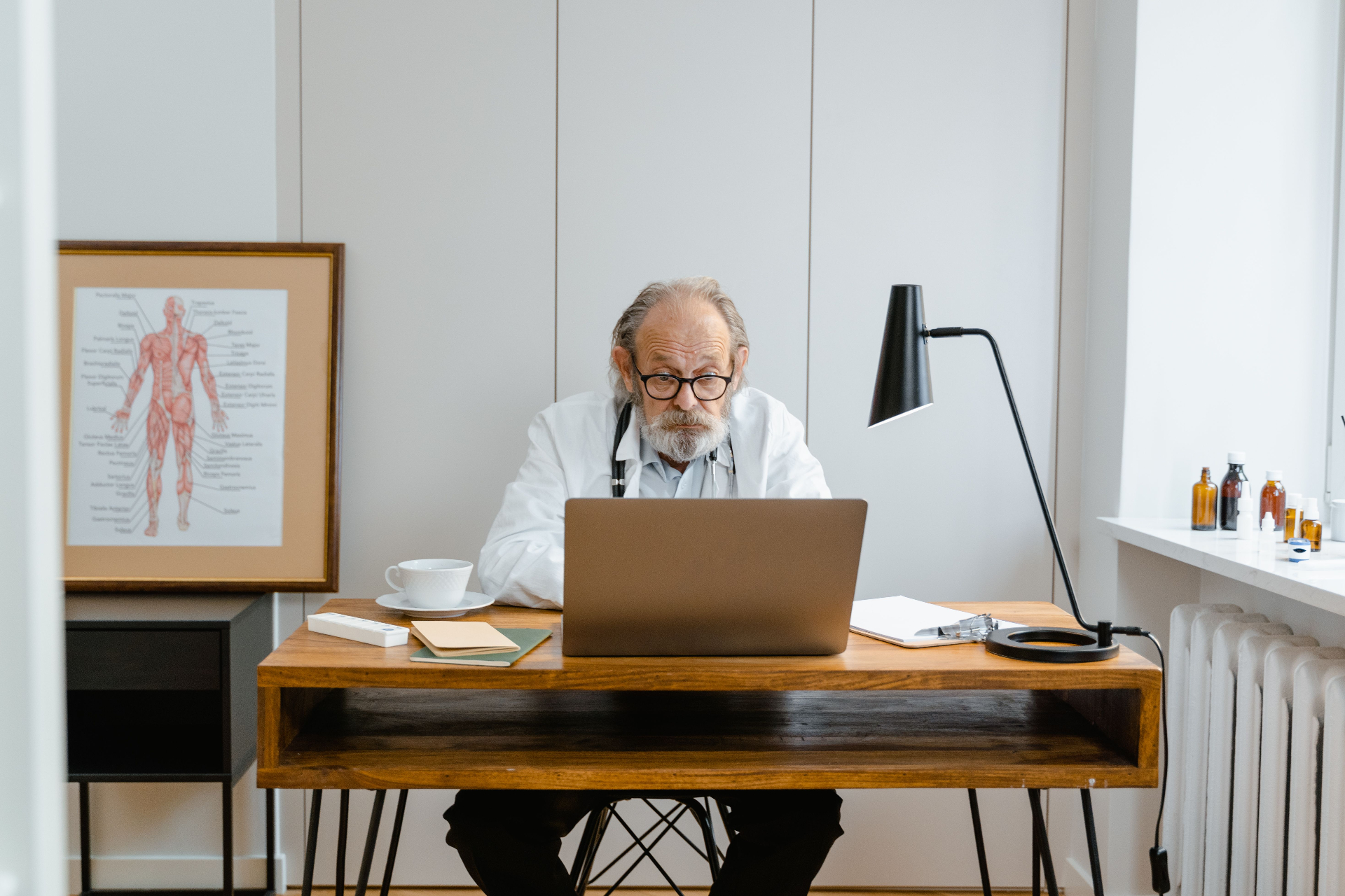 Médecin généraliste travaillant sur son ordinateur portable dans son cabinet